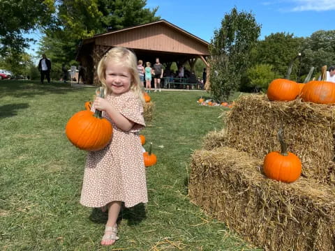 a girl standing next to pumpkins