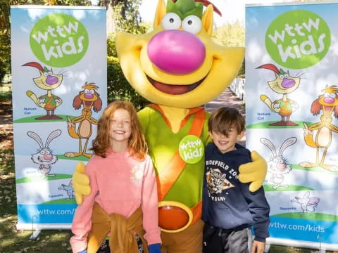 a boy and girl posing with a large cartoon character