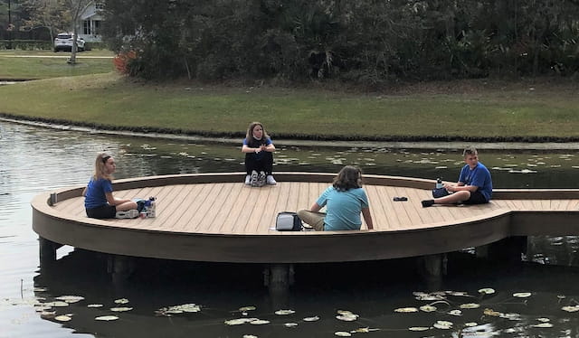 a group of people sitting on a dock in a lake