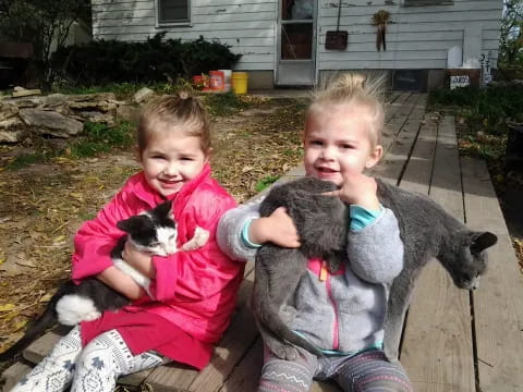 two children holding a cat