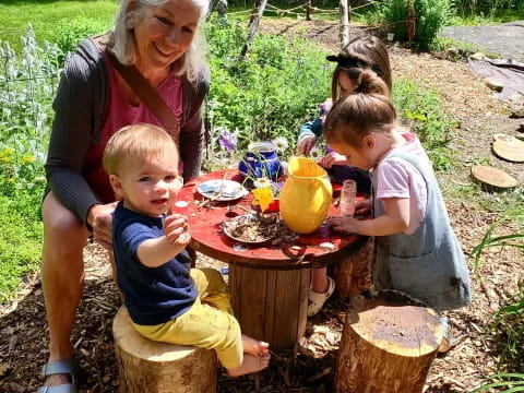 a person and several children sitting around a table outside