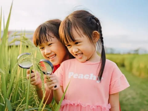 a couple of girls holding a pair of scissors in a field