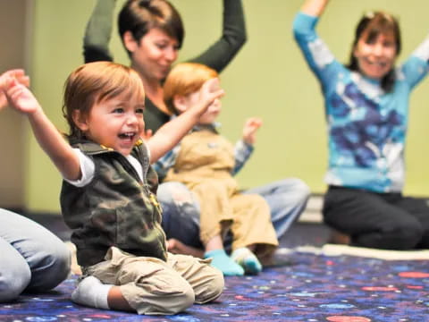 a group of people sitting on the floor with their hands up