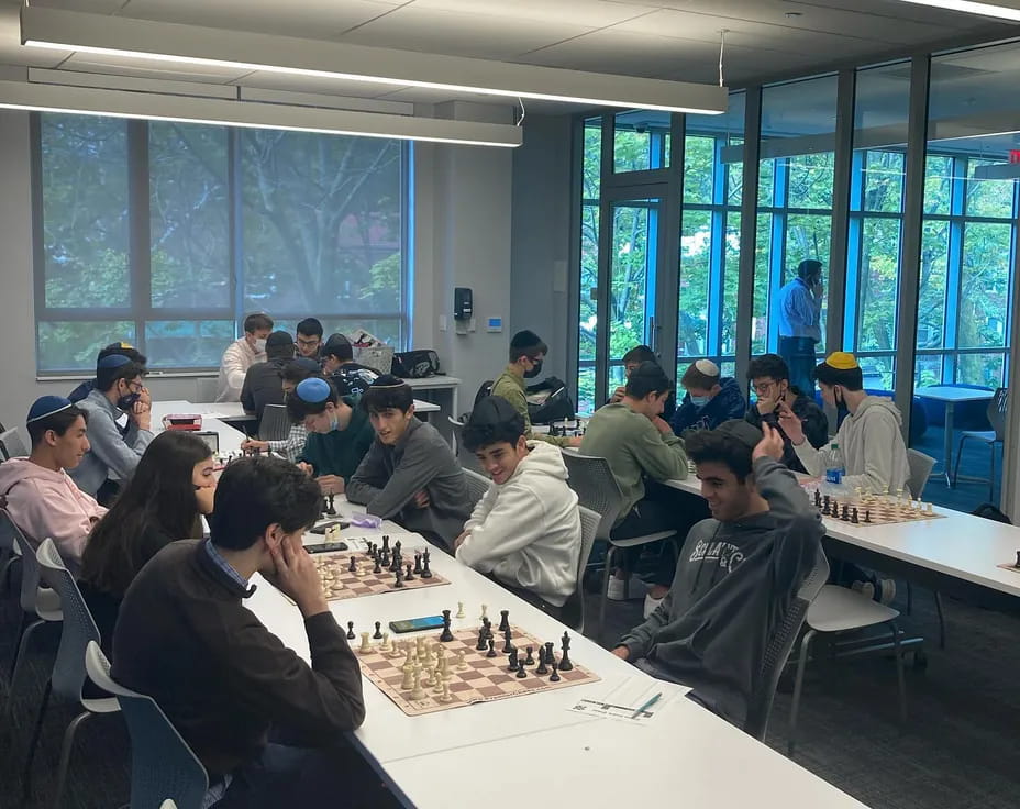 a group of people sitting around a table playing chess