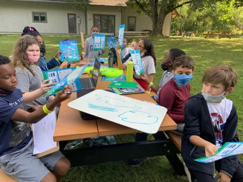 a group of children sitting at a table with books and paper