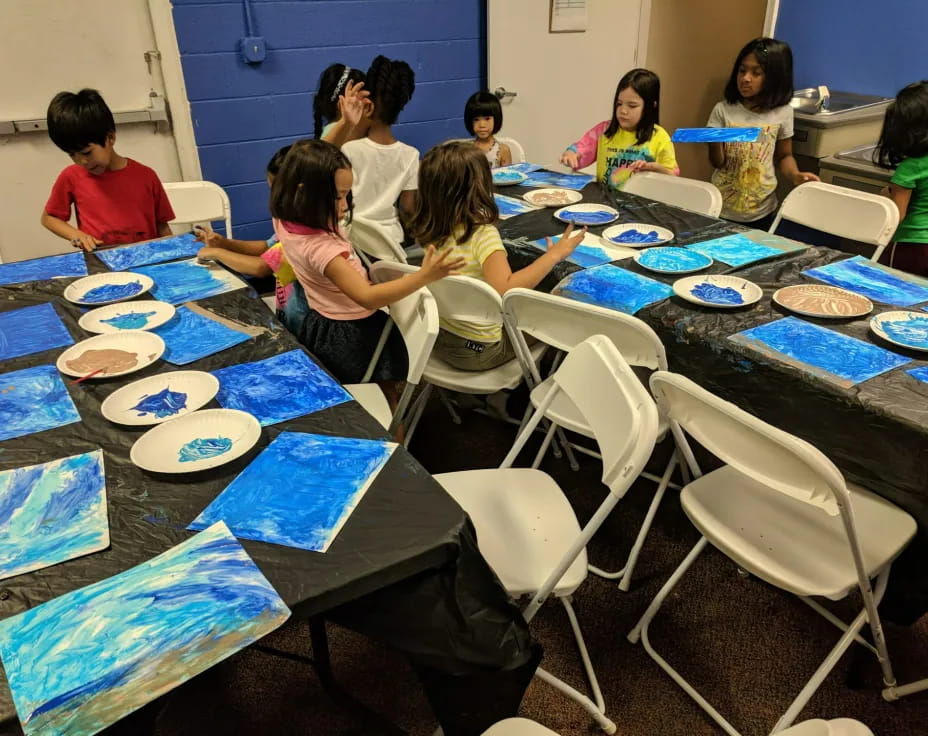 a group of children sitting around a table with plates on it