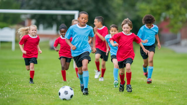 a group of kids compete over a football ball