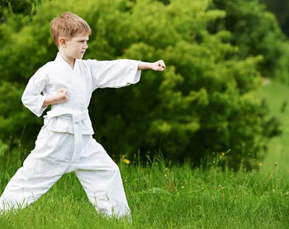 a boy in white clothes running in a grassy area