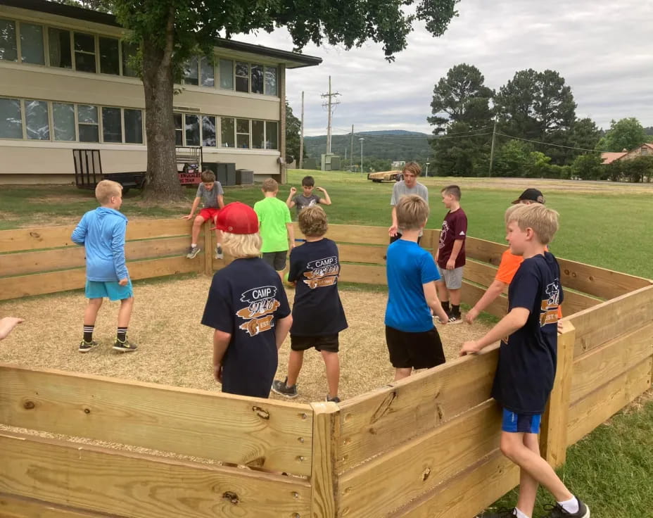 a group of kids standing on a wooden bench in front of a building