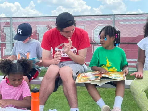 a group of people sitting on a bench eating pizza