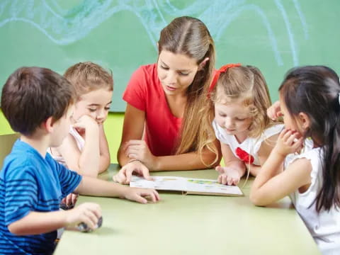 a group of children sitting at a table looking at a paper