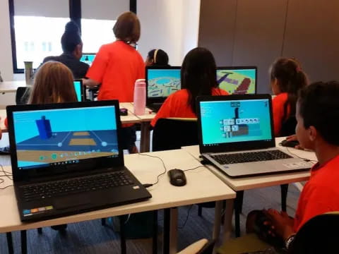 a group of people sitting at desks with laptops