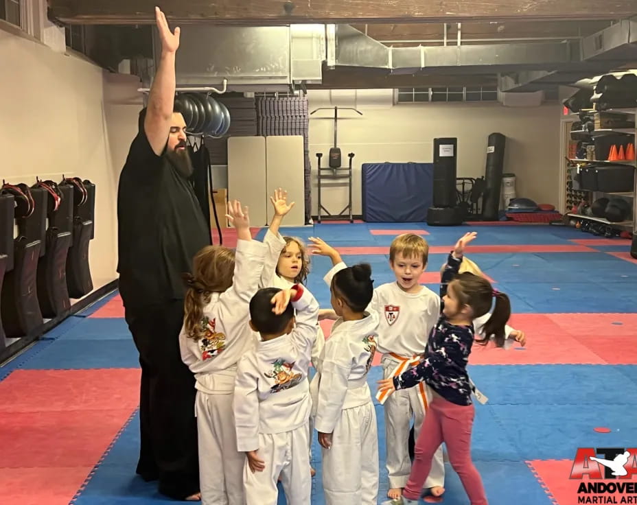 a man standing in front of a group of children in karate uniforms