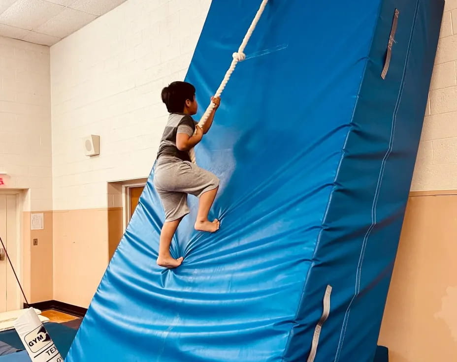 a boy climbing a blue tent