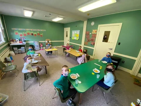a group of children sitting at tables in a classroom