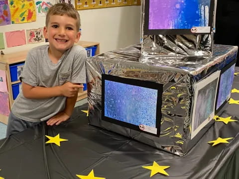 a boy sitting next to a computer