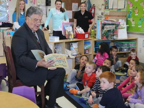 a person reading a book to a group of children