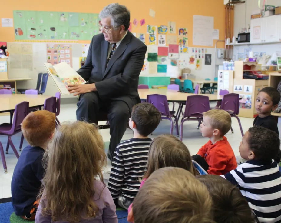 a person reading a book to a group of children