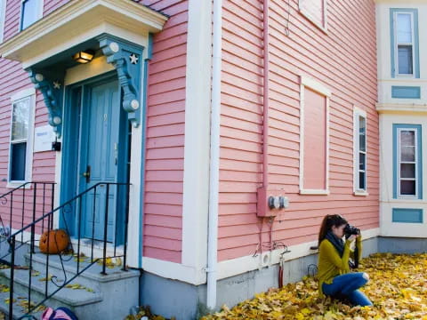 a person sitting on the ground next to a pink house