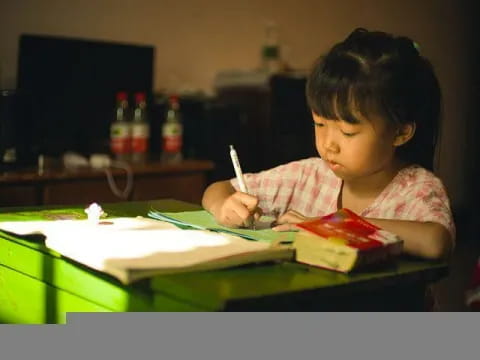 a young girl writing on a book