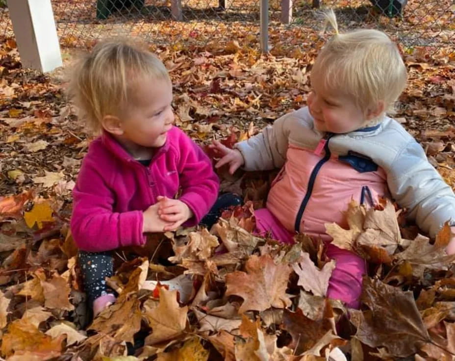 two children playing in leaves