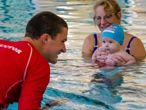 a man and woman with a baby in a pool