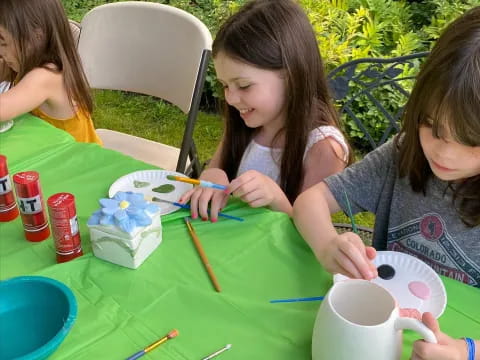 a group of girls sitting at a table painting