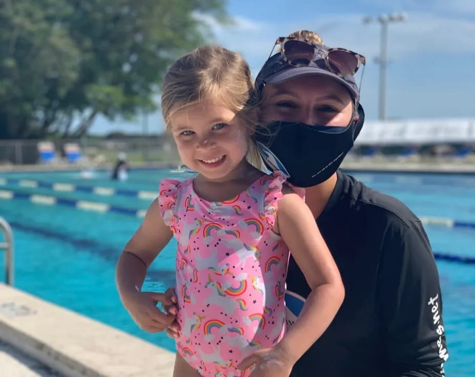 a person and a child posing for the camera by a pool