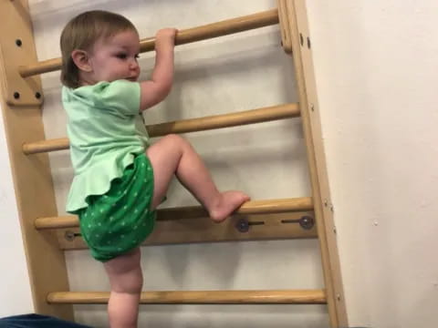 a baby climbing on a wooden structure