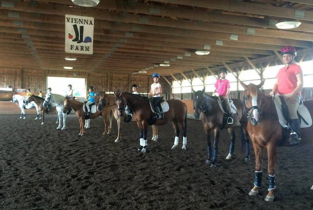 people riding horses in a barn