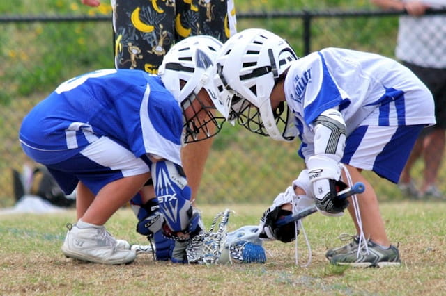 a couple of people playing lacrosse