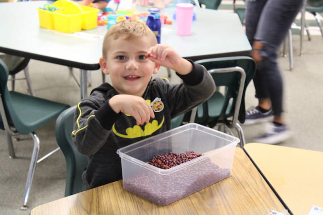 a boy sitting at a table with a tray of food