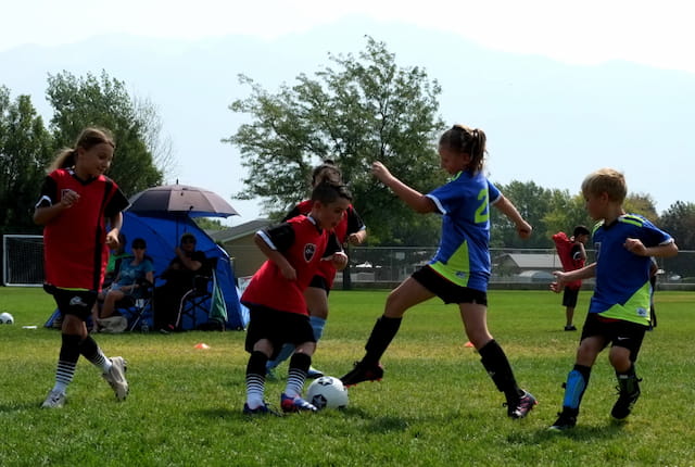 a group of kids compete over a football ball