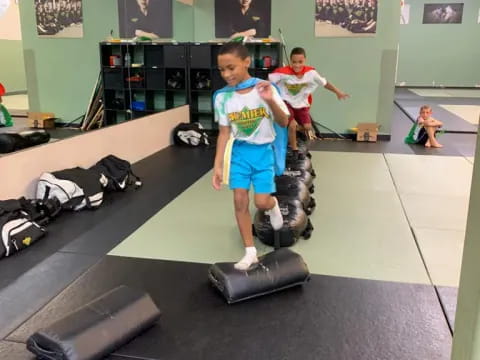 a couple of boys playing on exercise equipment in a gym