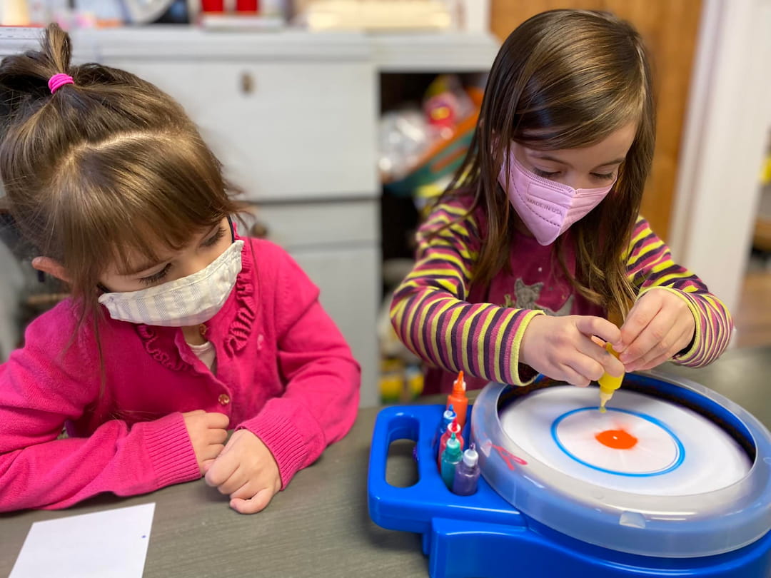 a couple of young girls playing with a toy