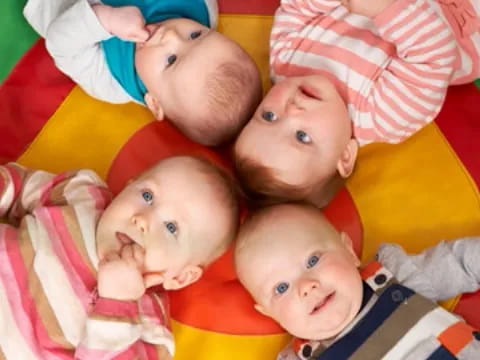 a group of babies lying on a colorful blanket