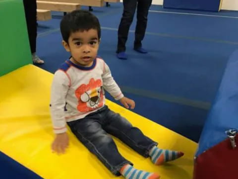 a boy sitting on a yellow mat