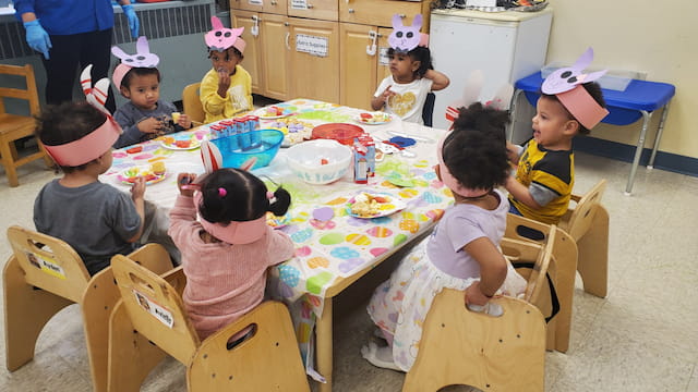 a group of children sitting around a table with food on it