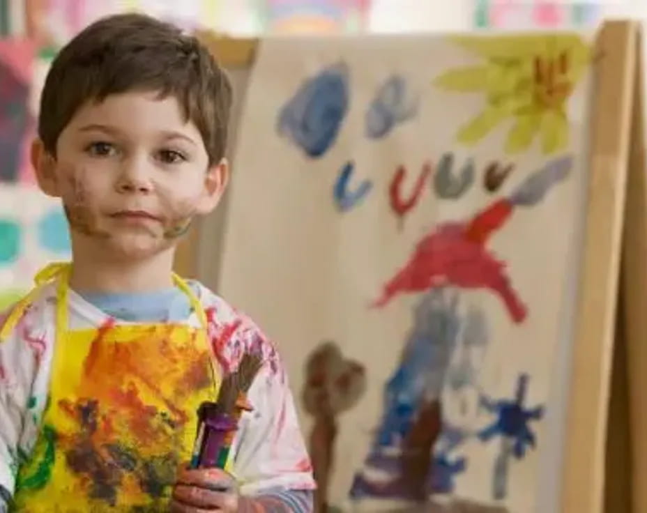 a child standing in front of a white board with colorful drawings