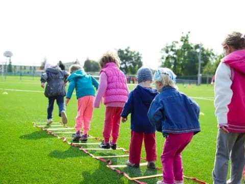 a group of children walking on a grass field