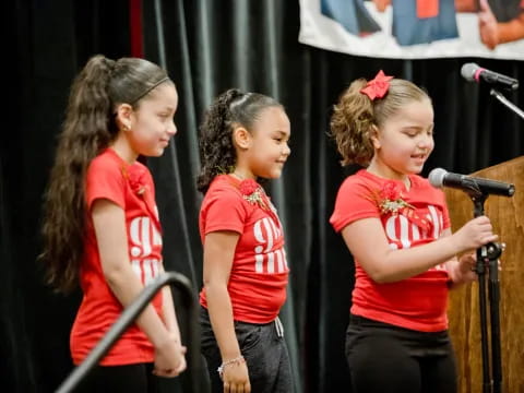 a group of girls singing into microphones