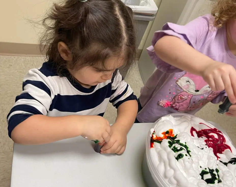 a couple of girls sit near a cake