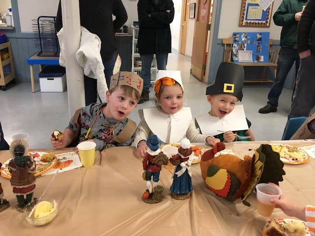a group of kids sitting at a table with food