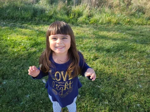 a girl standing in a grassy area