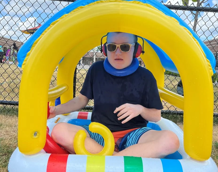 a boy sitting in a yellow and blue playground toy