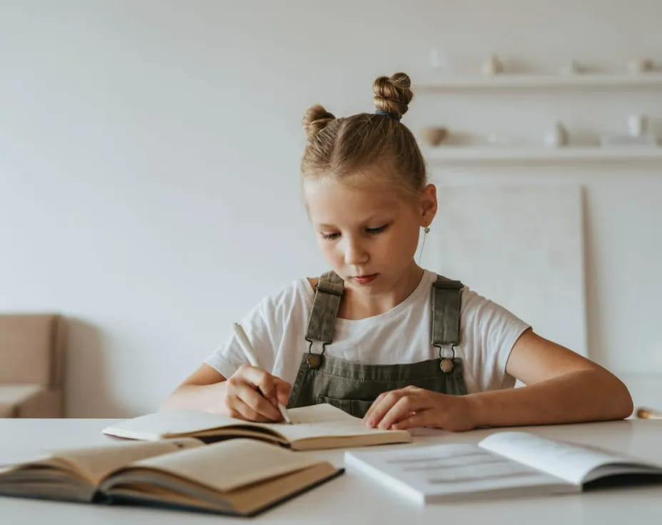 a young girl writing on a book