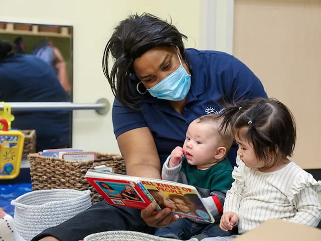 a person reading a book to a couple of children