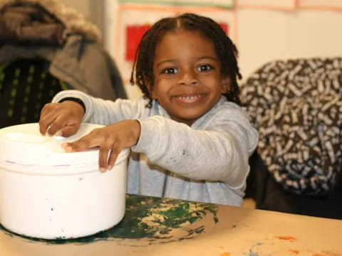 a young girl smiling and holding a bowl of food