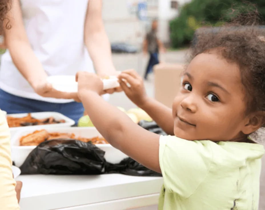 a child getting food from a table
