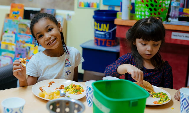 a couple of young girls eating at a table
